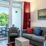 Wohnzimmer mit Sofa, Sessel und Balkon. Rote Vorhänge und Wandbild.