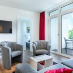 Wohnzimmer mit TV, Sitzgelegenheiten und Balkonzugang.