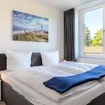 Schlafzimmer mit Doppelbett, Fenster und Wandbild mit Leuchtturm.