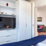 Schlafzimmer mit TV, Kleiderschrank und Blick in Wohnbereich.