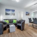 Wohn- und Essbereich mit Sofa, Stühlen und Wandbildern.