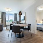 Wohnbereich mit Esstisch, Sofa und Schlafzimmer mit Bett.