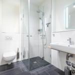 Badezimmer mit Dusche, Waschbecken und Toilette.