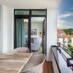 Terrasse mit Tisch und Stühlen, Blick auf Dächer und Grün.