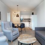 Wohnzimmer mit Sofa, Sessel und Küchenbereich im Hintergrund.