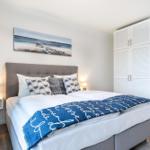 Schlafzimmer mit Doppelbett, Kleiderschrank und Wandbild.