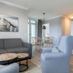 Wohn- und Essbereich mit Sofa, Sessel und Esstisch. Wandbild zeigt einen Steg.