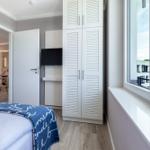 Schlafzimmer mit Bett, Kleiderschrank und Fenster. Durchgang zur Küche und Bad.