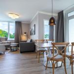 Wohn- und Essbereich mit Holzboden, Sitzgelegenheiten und Balkontür.