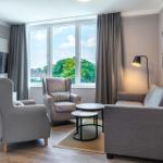 Wohnzimmer mit Sofa, zwei Sesseln und TV an der Wand.