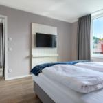 Zwei Betten, TV und Fenster mit Blick auf Dächer.