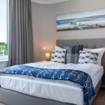 Schlafzimmer mit Bett, Nachttischen und Fensterblick auf Grün.