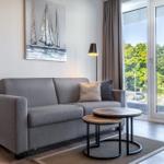 Ein Wohnzimmer mit grauem Sofa, zwei runden Tischen und Blick auf einen Balkon.