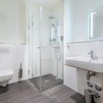 Badezimmer mit Dusche, Waschbecken und Toilette.