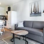 Wohnzimmer mit Sofa, Tisch und Küchenbereich im Hintergrund.