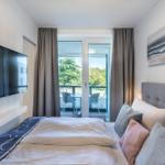 Schlafzimmer mit Bett, TV und Balkon mit Tisch und Stühlen.