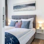 Schlafzimmer mit Bett, Kissen und Wandbild.