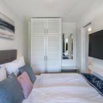 Schlafzimmer mit Bett, Kleiderschrank und Fernseher an der Wand.