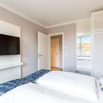 Schlafzimmer mit Bett, TV und Kleiderschrank. Blick auf Balkon und Dach.