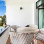 Terrasse mit runden Tisch und vier Stühlen. Holzfußboden und Blick auf Wohngebiet.