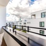 Terrasse mit Sitzgelegenheit und Blick auf moderne Gebäude.