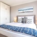 Schlafzimmer mit Doppelbett, Kleiderschrank und Wandbild.