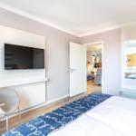 Schlafzimmer mit Bett, Fernseher und Blick in Wohnbereich.