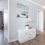 Flur mit Schrank, Wandbild und Pflanze. Tür führt in Schlafzimmer mit Fenster.