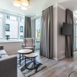 Wohnzimmer mit Sofa, Sessel und TV an der Wand.