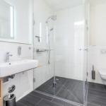 Badezimmer mit Dusche, Waschbecken und Toilette.