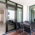 Terrasse mit Tisch und Stühlen, Zugang zum Innenraum über Schiebetüren.