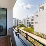 Terrasse mit Tisch und Blick auf moderne Wohnhäuser und Grünflächen.