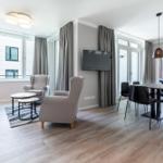 Wohn- und Essbereich mit Sofa, Sesseln, TV und Tisch mit Stühlen.