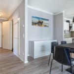 Essbereich mit Tisch und Stühlen, weiße Schränke und Wandbild.