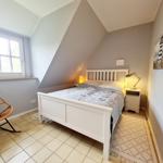 Schlafzimmer mit Dachschrägen, weißem Bett und Steintisch.