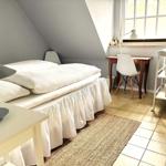 Schlafzimmer mit Doppelbett, Schreibtisch und Fenster.