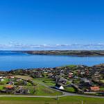 Panoramablick auf Küstenort mit Häusern und blauem Meer unter klarem Himmel.