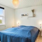 Schlafzimmer mit blauem Bett, Fenster und Wandregalen.