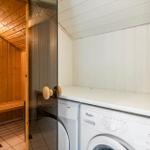 Waschmaschine und Trockner neben einer Sauna mit Holzwand und Bank.