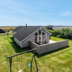 Moderne Holzhütte mit Terrasse und Spielplatz auf grünem Grundstück.
