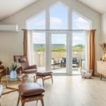 Wohnzimmer mit braunen Ledermöbeln und großem Fenster zur Terrasse.