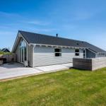 Moderne Villa mit Holzterrasse und Garten. Außenbereich mit Sitzgelegenheiten.