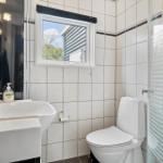 Badezimmer mit Toilette, Waschbecken und Dusche. Fenster mit Blick nach draußen.