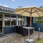 Terrasse mit Tisch, Stühlen und Sonnenschirm. Glastür führt ins Haus. Hinterhof mit Hecke.