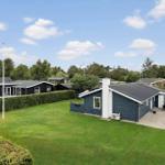 Modernes Ferienhaus mit Garten und Terrasse unter blauem Himmel.