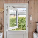 Küche mit Holzwand, geöffnetem Fenster und Kaffeemaschine.