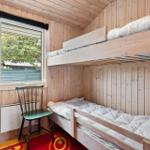 Zimmer mit Doppelstockbett, Holzwand und Fenster mit Blick auf Grün.