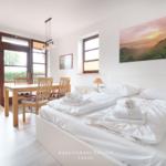 Ein Schlafzimmer mit Bett, Esstisch und Fenster zur Außenterrasse.