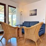 Wohnzimmer mit Sofa, zwei Rattanchairs und Blick auf Terrasse.