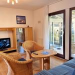 Wohnzimmer mit TV, Sitzgelegenheiten und Zugang zur Terrasse.